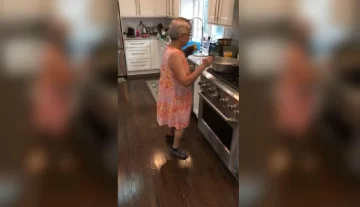 Una anciana se mueve al ritmo de la música mientras cocina Una anciana se mueve al ritmo de la música mientras cocina